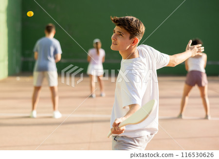 Young male pelota player hitting ball with wooden racket 116530626