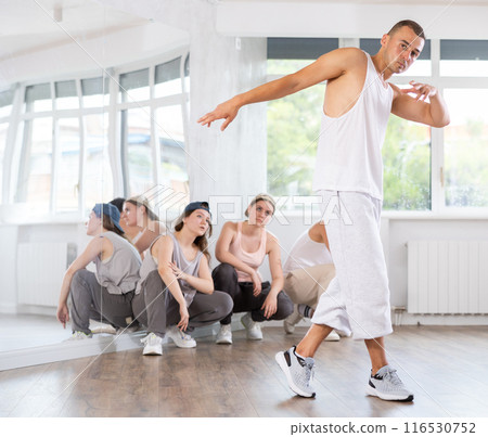 Visitors to studio, observe professional male break dance rendering of elements performances couch 116530752