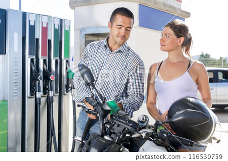 Caucasian man and woman refuelling motorbike in gas station 116530759