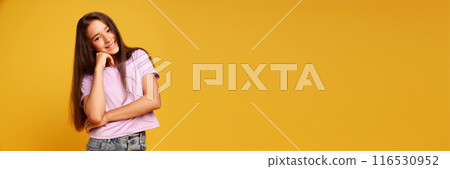 Portrait of pretty teen girl with brown long hair, wearing pink t-shirt, standing with cheerful smile against yellow studio background Portrait of pretty teen girl with brown long hair, wearing pink t-shirt, standing with cheerful smile against yellow studio background 116530952