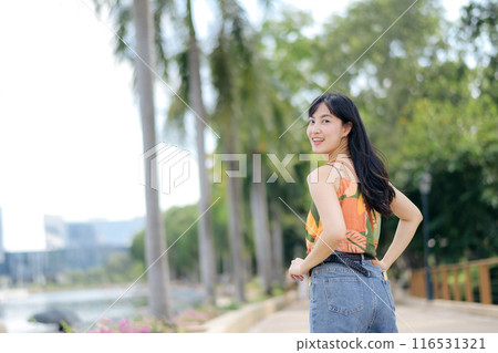 Happy young woman in urban setting, posing with a carefree smile, enjoying freedom and modern lifestyle. 116531321