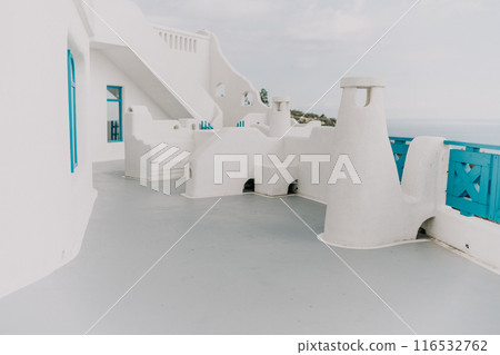 A white building with blue trim and a blue balcony. The balcony overlooks the ocean. The building is empty and the sky is cloudy. A white building with blue trim and a blue balcony. The balcony overlooks the ocean. The building is empty and the sky is cloudy. 116532762