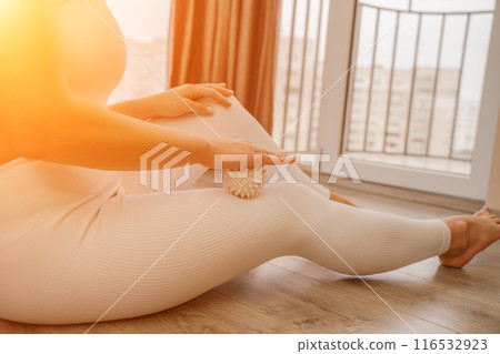 Athletic slim caucasian woman doing thigh self-massage with a massage ball indoors. Self-isolating massage Athletic slim caucasian woman doing thigh self-massage with a massage ball indoors. Self-isolating massage 116532923