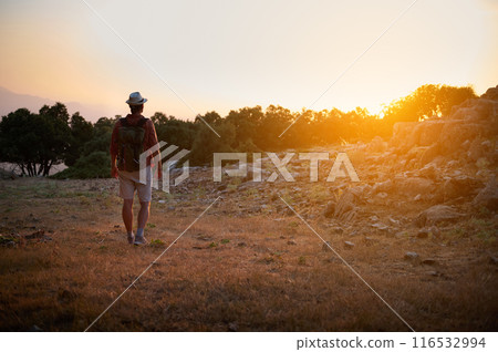 Backpacker exploring nature at sunset with hiking gear in mountain landscape Backpacker exploring nature at sunset with hiking gear in mountain landscape 116532994
