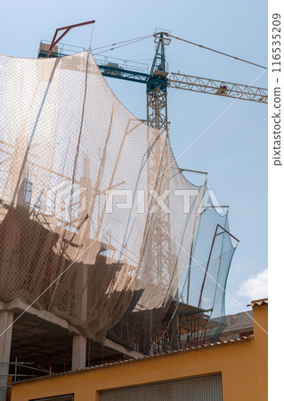 New building construction process. Safety nets and structural beams highlight ongoing work. Detailed shot of multi-level architecture. Ideal for articles on urban development, real estate investment. 116535209