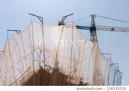 New building construction process. Safety nets and structural beams highlight ongoing work. Detailed shot of multi-level architecture. Ideal for articles on urban development, real estate investment. New building construction process. Safety nets and structural beams highlight ongoing work. Detailed shot of multi-level architecture. Ideal for articles on urban development, real estate investment. 116535210