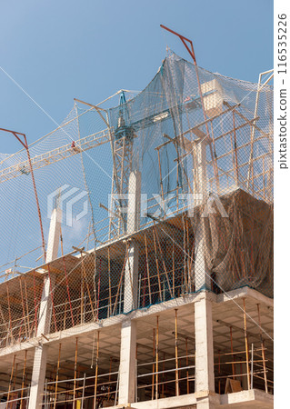 New building construction process. Safety nets and structural beams highlight ongoing work. Detailed shot of multi-level architecture. Ideal for articles on urban development, real estate investment. 116535226