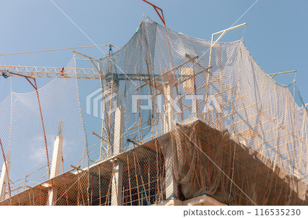 Captivating image of construction site under a bright sky, featuring crane, safety nets, and framework, ideal for themes related to urban development, construction safety, and architectural projects. Captivating image of construction site under a bright sky, featuring crane, safety nets, and framework, ideal for themes related to urban development, construction safety, and architectural projects. 116535230