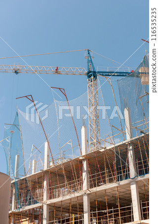 New building construction process. Safety nets, structural beams highlight ongoing work. Multi-level architecture. Ideal for articles on urban development, real estate investment. Copy space for text. 116535235