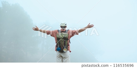 Man hiking in misty forest with arms outstretched embracing nature Man hiking in misty forest with arms outstretched embracing nature 116535696