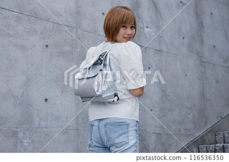 背著防災背包的婦女的後方視圖。混凝土建築背景 116536350