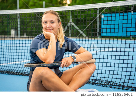Portrait of professional female tennis player with the tennis racket on outside court Portrait of professional female tennis player with the tennis racket on outside court 116536461