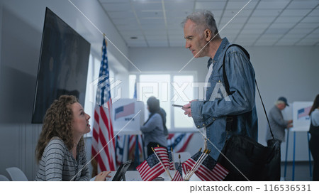 Caucasian American citizen stands near registration table at polling station 116536531