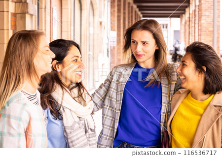 Young women friends happily spending time together outside, showing unity and warmth in their bond 116536717