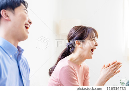 Couple laughing out loud watching TV Couple laughing out loud watching TV 116536783