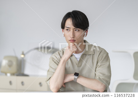 一個20多歲的男人,戴著耳機,表情嚴肅地思考著 一個20多歲的男人,戴著耳機,表情嚴肅地思考著 116537228