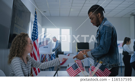 African American male voter stands near registration table at polling station African American male voter stands near registration table at polling station 116537595