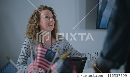 Female polling officer consults African American voter, uses tablet computer 116537599