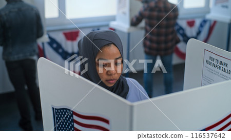 Muslim woman comes to voting booth to fill out ballot paper 116537642