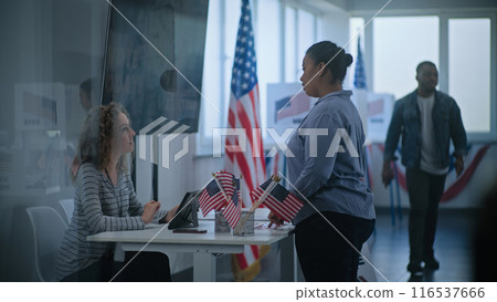 African American woman approaches registration table at polling station 116537666