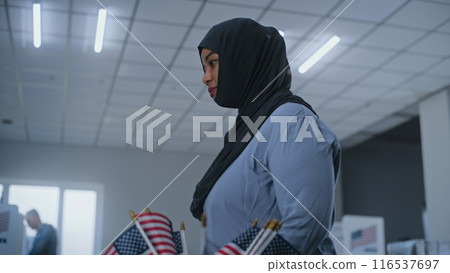Arabic woman stands near registration table at polling station and talks to polling officer 116537697