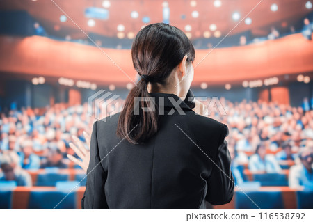 Woman speaking into a microphone in front of a crowd Woman speaking into a microphone in front of a crowd 116538792