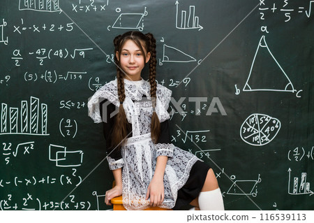 Schoolgirl teenager in school uniform with white apron, festive clothes for school graduation Schoolgirl teenager in school uniform with white apron, festive clothes for school graduation 116539113