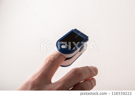 Pulse oximeter close up on a pastel background. Measurement of oxygen saturation in blood and heart rate. Health check up concept. Healthcare. Pneumonia and COVID-19 virus. High quality photo 116539222