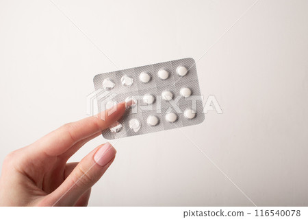Pills, blister pack in hand close up isolated on white background. Medicine dose. Medicinal treatment, vitamins, supplements, contraceptive pills. Womens health. Copy space, banner. High quality photo Pills, blister pack in hand close up isolated on white background. Medicine dose. Medicinal treatment, vitamins, supplements, contraceptive pills. Womens health. Copy space, banner. High quality photo 116540078