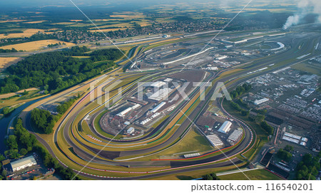 Aerial view of large empty racetrack with multiple turns, long straights and sharp turns, track surrounded by green fields Aerial view of large empty racetrack with multiple turns, long straights and sharp turns, track surrounded by green fields 116540201