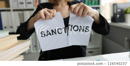 Woman tearing sheet of paper with sanctions inscription 116540237