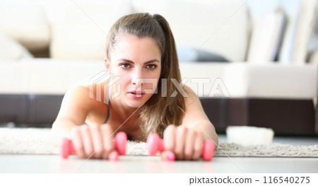 Cute young woman performing exercise with dumbbells Cute young woman performing exercise with dumbbells 116540275