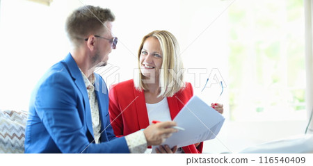 Smiling businessman and businesswoman discussing good deal Smiling businessman and businesswoman discussing good deal 116540409