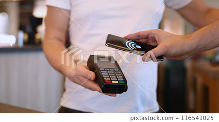 Man paying with mobile phone over pos terminal with nfc technology 116541025