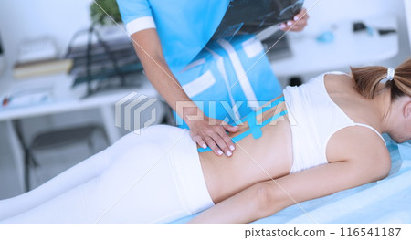 Doctor examine x ray scan, woman with back damage, massaging hurting spots, using taping 116541187
