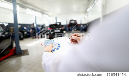 Male worker writing machine diagnostic data in garage Male worker writing machine diagnostic data in garage 116541454
