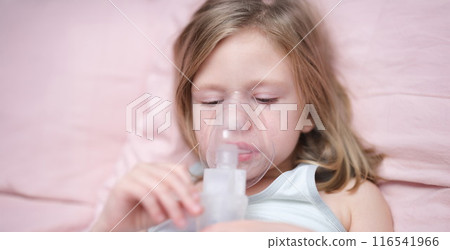 Little sad girl having inhalation for easing cough 116541966