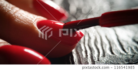 Master painting nails with bright red varnish to client closeup Master painting nails with bright red varnish to client closeup 116541985
