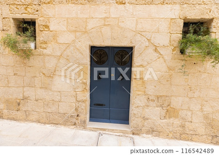 Image of an old, worn door in a Mediterranean house facade 116542489