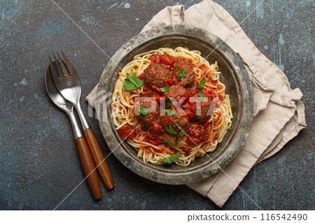 Spaghetti and meatballs with tomato sauce served on rustic plate with cutlery top view, Italian cuisine Spaghetti and meatballs with tomato sauce served on rustic plate with cutlery top view, Italian cuisine 116542490