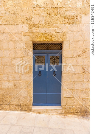 Image of an old, worn door in a Mediterranean house facade 116542491
