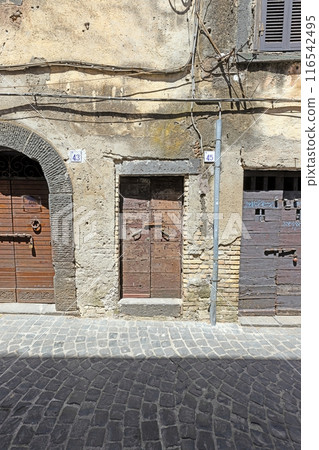 Image of an old, worn door in a Mediterranean house facade Image of an old, worn door in a Mediterranean house facade 116542495
