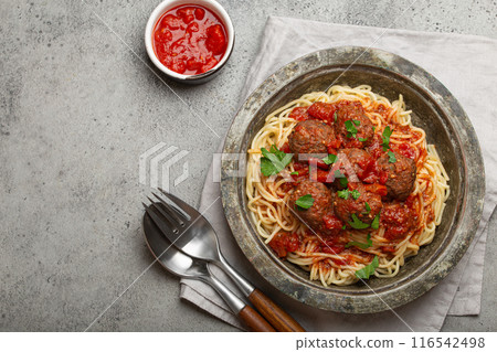 Spaghetti and meatballs with tomato sauce served on rustic plate with cutlery top view copy space, Italian cuisine Spaghetti and meatballs with tomato sauce served on rustic plate with cutlery top view copy space, Italian cuisine 116542498