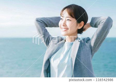 A woman stretching with the sea in the background 116542986
