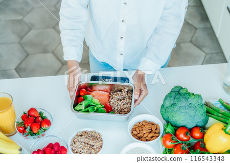 Healthy diet plan for weight loss, daily ready meal menu. Close up Woman weighing lunch box cooked in advance,ready to eat on kitchen scale. Balanced portion with healthy dish. Pre-cooking concept Healthy diet plan for weight loss, daily ready meal menu. Close up Woman weighing lunch box cooked in advance,ready to eat on kitchen scale. Balanced portion with healthy dish. Pre-cooking concept 116543348