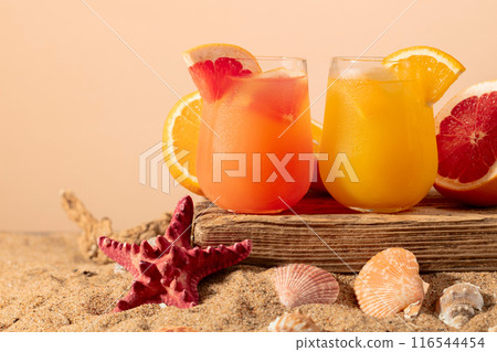 Grapefruit and orange cocktails with fresh fruits on a beach. Grapefruit and orange cocktails with fresh fruits on a beach. 116544454