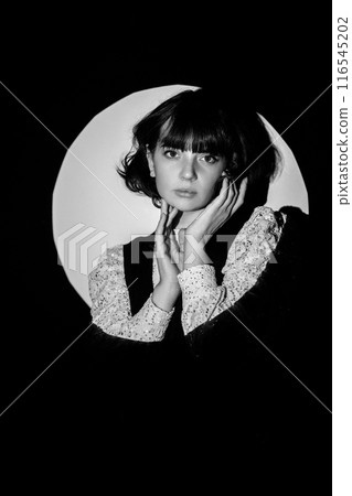 Young Caucasian woman posing in a spotlight circle in a photo studio. 116545202