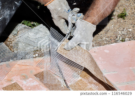 Construction worker uses scissors to cut flexible panel with imitation brickwork, made of marble chips with acrylic and reinforced with plastic mesh. Construction worker uses scissors to cut flexible panel with imitation brickwork, made of marble chips with acrylic and reinforced with plastic mesh. 116546029