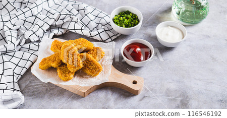 Crispy nuggets on paper on a board and sauce in a bowl on the table web banner Crispy nuggets on paper on a board and sauce in a bowl on the table web banner 116546192