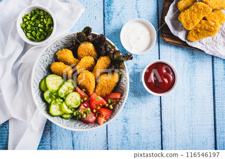 Bowl with crispy nuggets, tomato and cucumber on the table top view 116546197
